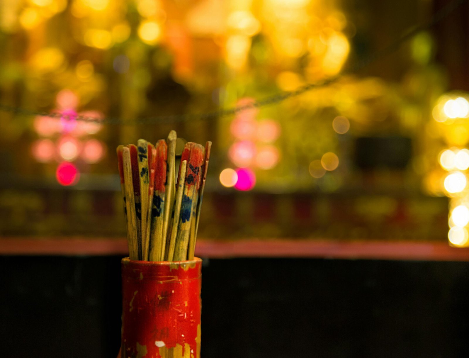 Close-up of Chinese fortune sticks in a jar, with blurred bokeh background for cultural themes.