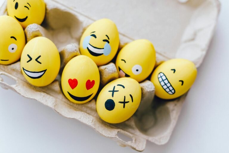 Bright yellow Easter eggs painted with fun emoticon faces in an egg carton.